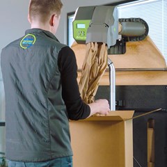  A person using a Quantum Pro packaging machine to dispense protective paper into a cardboard box for efficient packing.